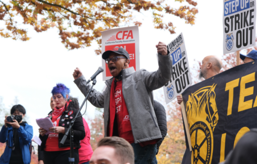 People holding signs at a rally outside.